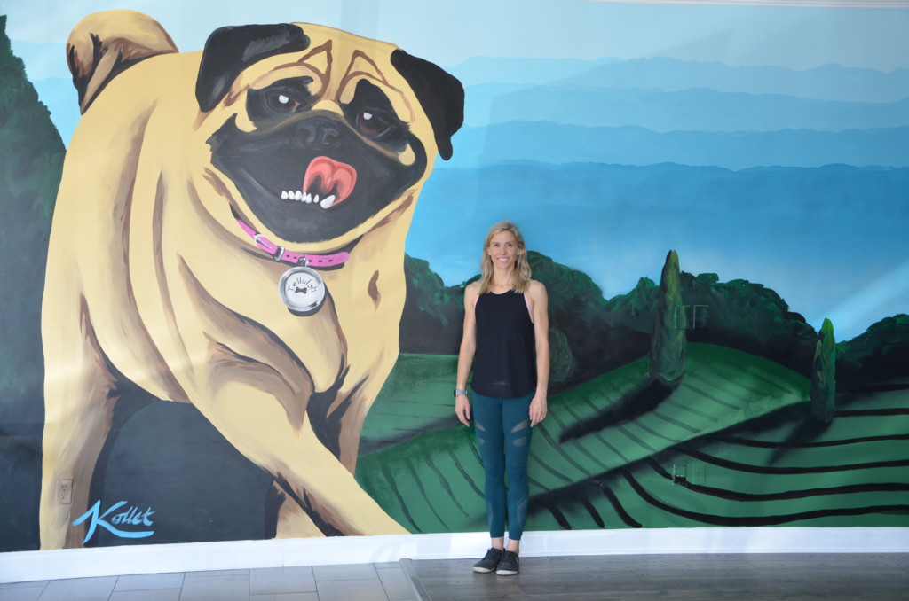 Owner Ashley Guy standing in front of dog wall mural